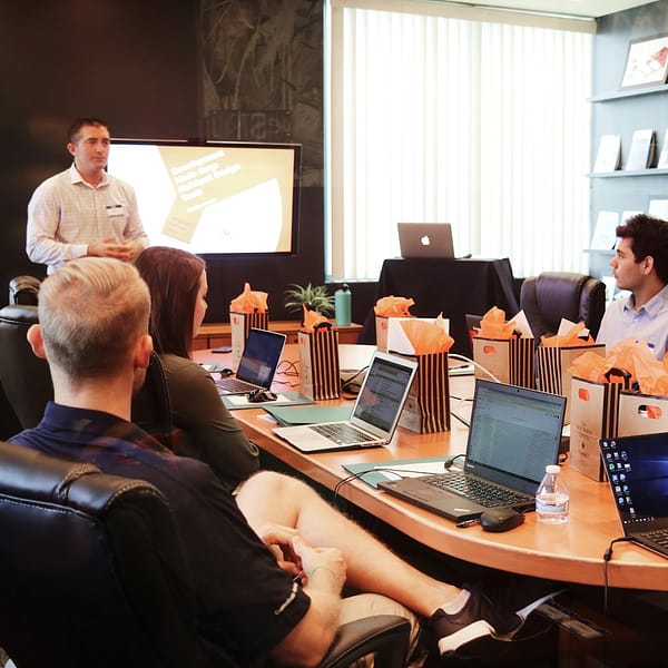 Voob.com.ng 12 man standing in front of people sitting beside table with laptop computers