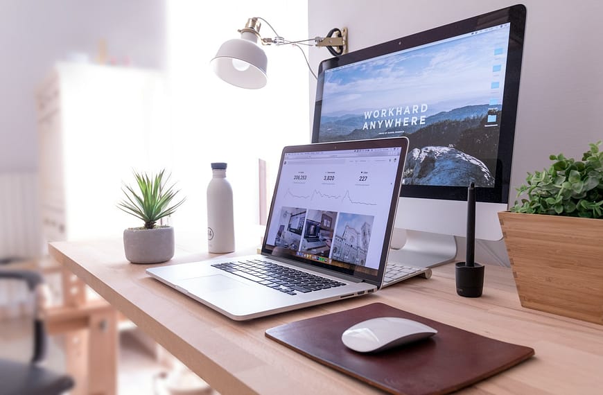 MacBook Pro on table beside white iMac and Magic Mouse