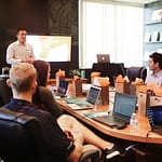man standing in front of people sitting beside table with laptop computers