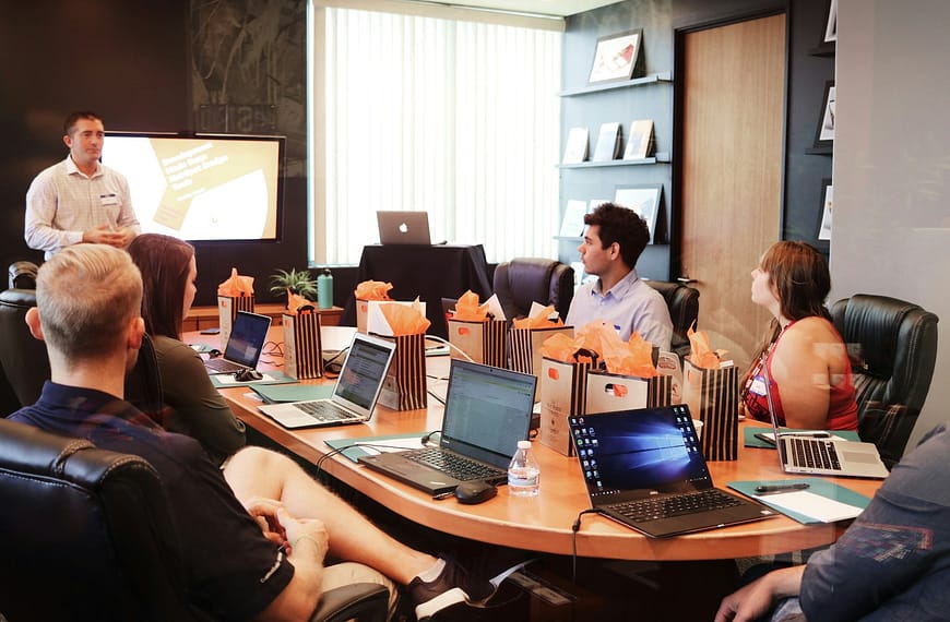 man standing in front of people sitting beside table with laptop computers