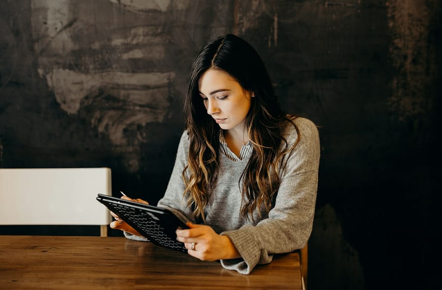 woman wearing white dress shirt using holding black leather case on brown wooden table